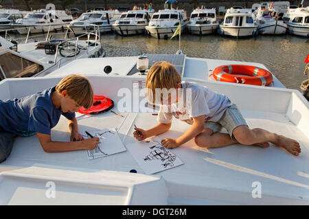 Zwei jungen, die Zeichnung auf einem Hausboot in einem Hafen auf dem Canal du Midi, Carcassonne, Region Languedoc-Roussillon, Frankreich Stockfoto