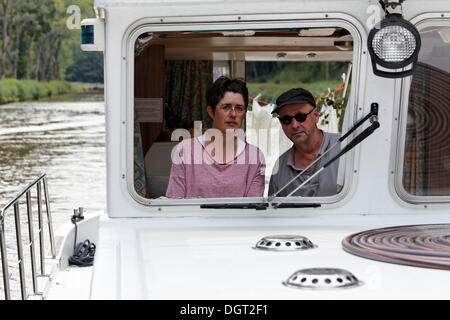 Frau und Mann am Steuer einer Pénichette, ein Hausboot auf dem Canal des Vosges, früher Canal de l ' est, Fontenoy-le-Château Stockfoto