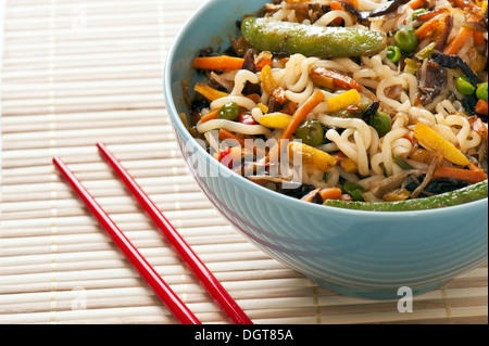 Asiatische Nudeln und gebratenes Gemüse in Schüssel mit Stäbchen Stockfoto