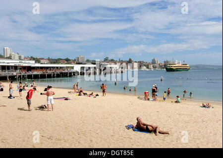 Kleine Strand von Manly Wharf, hinten eine Fähre in Manly Cove, North Sydney, New South Wales, NSW, Australien Stockfoto