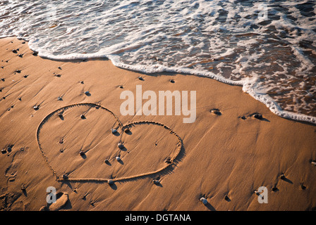 Herzform geschrieben am Sand mit Wasser im Hintergrund Stockfoto
