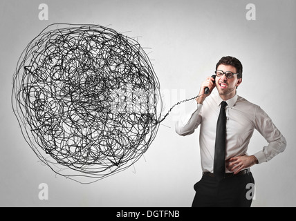 Kaufmännische Angestellte mit einem Telefon mit dem Draht sehr verwirrt Stockfoto