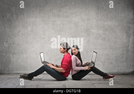 Junges Paar Rücken an Rücken mit einem laptop Stockfoto