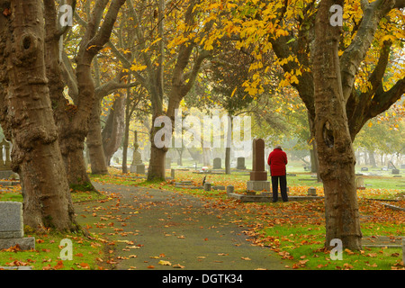 Ältere Frau besuchen Grab auf dem Ross Bay Cemetery im Herbst-Victoria, British Columbia, Kanada. Stockfoto