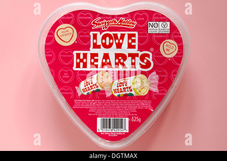 Swizzels Matlow Love Hearts Süßigkeiten Bonbons in herzförmiger Plastikbehälter-Wanne isoliert auf rosa Hintergrund - Blick von oben auf - liebes Herz Stockfoto