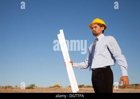 Geschäftsmann mit Blaupausen auf dem Feld Stockfoto