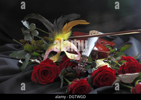 Violine, eine Maske und eine Rose auf einem schwarzen Hintergrund Stockfoto