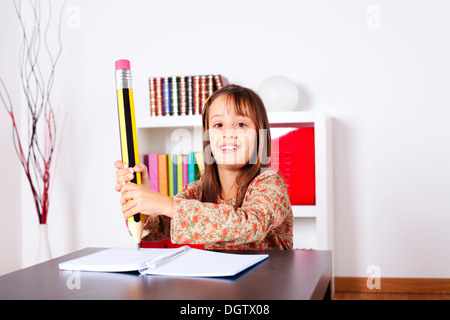 Kleines Mädchen in ihrem Haus mit einem riesigen Bleistift schreiben Stockfoto