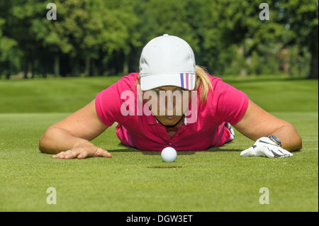 Golfer Golfball ins Loch bläst Stockfoto