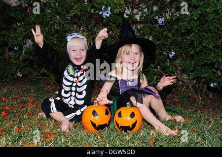 Junges Mädchen gekleidet als Hexe und junge als ein Skelett für Halloween verkleidet. Stockfoto