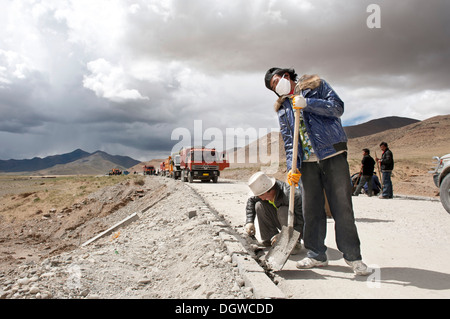 Straßenbau, tibetische Bauarbeiter mit Schaufeln Arbeiten unterwegs G 219, China National Highway 219 Stockfoto