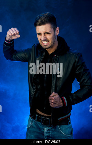 Junger Mann trägt eine schwarze Lederjacke mit einem aggressiv oder wütend Ausdruck Stockfoto