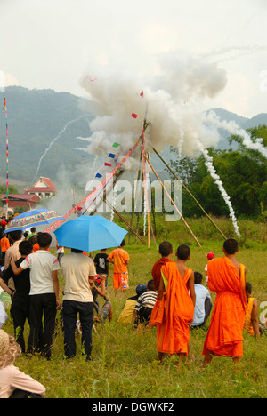 Festival, Rakete abfeuern, bang Fai, Start und die Explosion einer Rakete auf der Startrampe, Mönche in orangefarbenen Gewändern auf Stockfoto