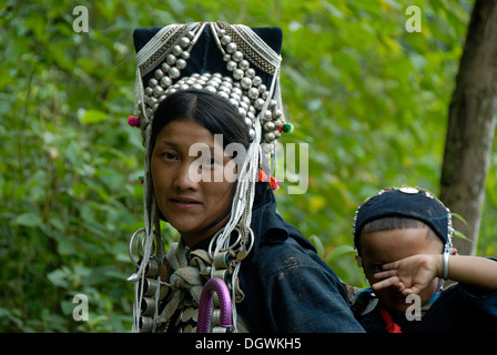 Porträt, Frau von der Volksgruppe der Akha Nuqui, Mutter und Kind, traditionelle Kleidung, Kopfbedeckung Stockfoto