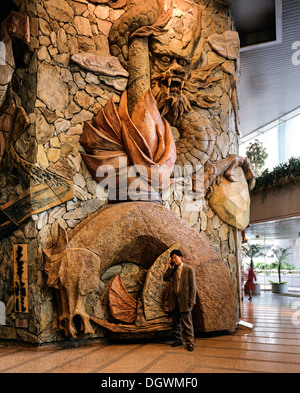 Lobby des Lippo Centre, Kunstwerke aus Stein mit einem Mann mit einem Mobiltelefon stehen im Vordergrund, Detail, Glasfassade Stockfoto