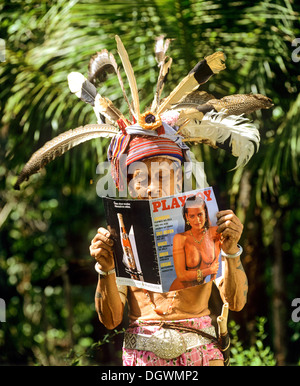 Kopf Hinters der ethnischen Gruppe der Iban Leute lesen ein Schürzenheld Zeitschrift, Skrang Fluss, Rajang, Sarawak, Malaysia, Borneo Stockfoto
