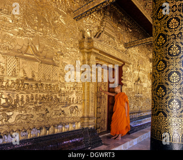 Mönch stehend an den vergoldeten Türen der Tempel Wat Mai, Luang Prabang, der Provinz Luang Prabang, Laos Stockfoto