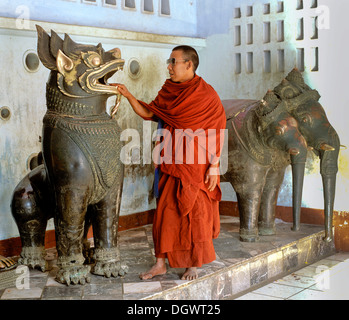 Mönch, indem seine hand in das Maul des Löwenstatue, vor einer Statue von Airävata, die dreiköpfigen Elefanten Stockfoto