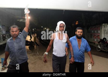 Dhaka, Bangladesch. 26 Okt, 2013. Kollege hilft Alal, ein Fahrer eines auto Rikscha, zu einem Operationssaal in Dhaka Medical College Hospital, nachdem er in einem Bombenattentat in Dhaka, Oktober 26, 2013 verletzt wurde. Pro-Streik Aktivisten warfen rohe Bomben, mutwillig zerstört und das Feuer auf mindestens 13 Fahrzeuge und mehr als 50 Menschen in Dhaka verletzt wurden. Bangladesh Nationalist Party (BNP) und die Verbündeten für drei Tag landesweite Streik von Sonntag genannt wird, eine geschäftsführende Regierung fordert, die lokalen Medien berichtet. Stockfoto