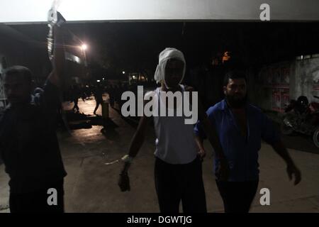 Dhaka, Bangladesch. 26 Okt, 2013. Kollege hilft Alal, ein Fahrer eines auto Rikscha, zu einem Operationssaal in Dhaka Medical College Hospital, nachdem er in einem Bombenattentat in Dhaka, Oktober 26, 2013 verletzt wurde. Pro-Streik Aktivisten warfen rohe Bomben, mutwillig zerstört und das Feuer auf mindestens 13 Fahrzeuge und mehr als 50 Menschen in Dhaka verletzt wurden. Bangladesh Nationalist Party (BNP) und die Verbündeten für drei Tag landesweite Streik von Sonntag genannt wird, eine geschäftsführende Regierung fordert, die lokalen Medien berichtet. Stockfoto