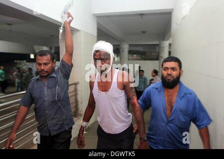 Dhaka, Bangladesch. 26 Okt, 2013. Kollege hilft Alal, ein Fahrer eines auto Rikscha, zu einem Operationssaal in Dhaka Medical College Hospital, nachdem er in einem Bombenattentat in Dhaka, Oktober 26, 2013 verletzt wurde. Pro-Streik Aktivisten warfen rohe Bomben, mutwillig zerstört und das Feuer auf mindestens 13 Fahrzeuge und mehr als 50 Menschen in Dhaka verletzt wurden. Bangladesh Nationalist Party (BNP) und die Verbündeten für drei Tag landesweite Streik von Sonntag genannt wird, eine geschäftsführende Regierung fordert, die lokalen Medien berichtet. Stockfoto