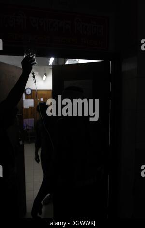 Dhaka, Bangladesch. 26 Okt, 2013. Ein Kollege hilft Alal, ein Fahrer eines auto Rikscha, zu einem Operationssaal in Dhaka Medical College Hospital, nachdem er in einem Bombenattentat in Dhaka, Oktober 26, 2013 verletzt wurde. Pro-Streik Aktivisten warfen rohe Bomben, mutwillig zerstört und das Feuer auf mindestens 13 Fahrzeuge und mehr als 50 Menschen in Dhaka verletzt wurden. Bangladesh Nationalist Party (BNP) und die Verbündeten für drei Tag landesweite Streik von Sonntag genannt, fordern Sie eine geschäftsführende Regierung, lokale Medien berichteten Stockfoto