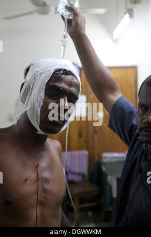 Dhaka, Bangladesch. 26 Okt, 2013. Ein Kollege hilft Alal, ein Fahrer eines auto Rikscha, zu einem Operationssaal in Dhaka Medical College Hospital, nachdem er in einem Bombenattentat in Dhaka, Oktober 26, 2013 verletzt wurde. Pro-Streik Aktivisten warfen rohe Bomben, mutwillig zerstört und das Feuer auf mindestens 13 Fahrzeuge und mehr als 50 Menschen in Dhaka verletzt wurden. Bangladesh Nationalist Party (BNP) und die Verbündeten für drei Tag landesweite Streik von Sonntag genannt, fordern Sie eine geschäftsführende Regierung, lokale Medien berichteten Stockfoto