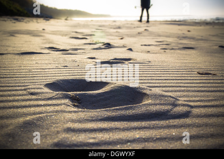 Fußabdruck im Sand und die Figur eines Mannes pflegen, Nordic-walking Stockfoto