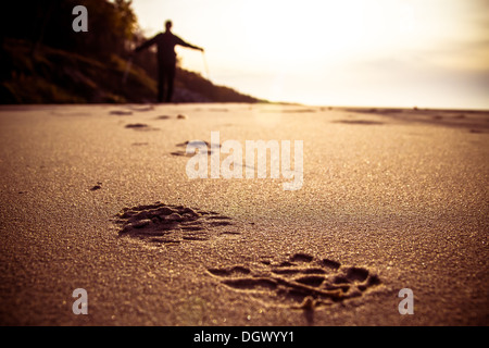 Fußabdruck im Sand und die Figur eines Mannes pflegen, Nordic-walking Stockfoto