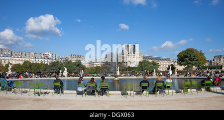 Leute genießen Herbst Sonnenschein um einen Teich (Grand Bassin Rond) im Jardin des Tuileries Paris. Der Louvre im Hintergrund Stockfoto