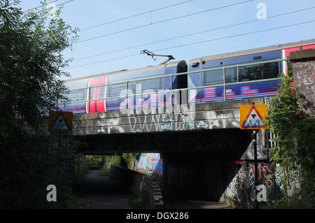 Erster Hauptstadt verbinden Zug überfährt Graffiti Bridge, Bedford Stockfoto