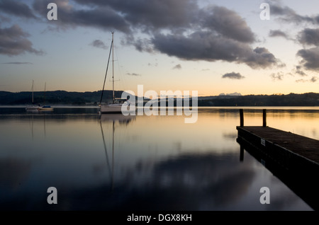 Am späten Abend auf Windermere Lake kurz nach Sonnenuntergang mit wenigen Yachten, ruhige Wasser und eine Anlegestelle. Stockfoto