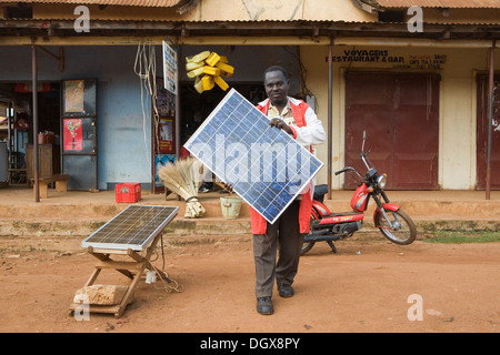 Herr Tinkasimire, Besitzer eines elektrischen Shop bietet Produkte wie Premier Modul Sonnenkollektoren, Masindi, Uganda, Afrika Stockfoto
