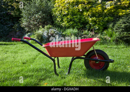 Rote Schubkarre in einem sonnigen s englischen Garten. Hautnah. Stockfoto