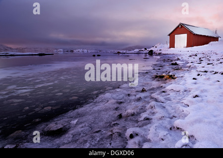 Fischerhütte am eisbedeckten Ufer an einem Fjord im Abendlicht, Tromsø, Nordnorwegen, Troms, Norwegen Stockfoto