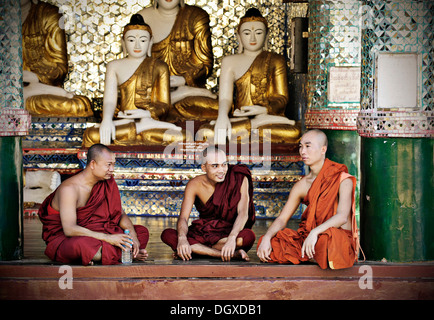 Buddhistische Mönche sitzen vor Buddha-Statuen in der Shwedagon-Pagode, Yangon, Birma auch bekannt als Myanmar, Südostasien Stockfoto