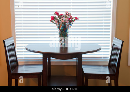 Esstisch und Stühle dekoriert mit Blumen in den beleuchteten Innenraum Stockfoto