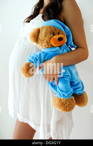 Frau mit einem schwangeren Bauch halten einen Teddybär Stockfoto