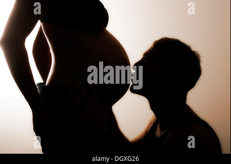 Mann den schwangeren Bauch seiner Frau zu küssen, silhouette Stockfoto