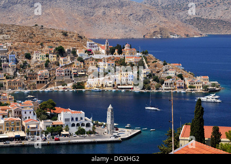 Mit Blick auf den malerischen Häusern und der Uhrturm von der kleinen Insel Symi in der Nähe von Rhodos, Griechenland, Europa Stockfoto