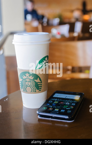 Starbucks Kaffee Tasse und ein Samsung Galaxy Smartphone auf einem Tisch in einem Starbucks. Stockfoto