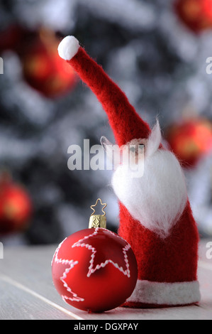 Weihnachtskugel rot und ein Filz Santa Claus vor einem Weihnachtsbaum Stockfoto