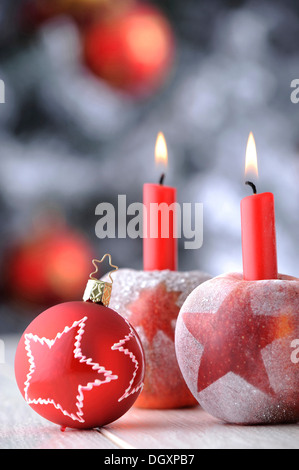 Rote Christbaumkugel mit Äpfeln und Kerzen vor einem Weihnachtsbaum Stockfoto