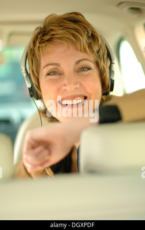 Business-Frau mit Kopfhörern in einem Auto sitzen Stockfoto