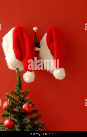 Zwei Santa Hüte hängen nostalgisch Kleiderhaken, Weihnachtsbaum am vorderen Stockfoto