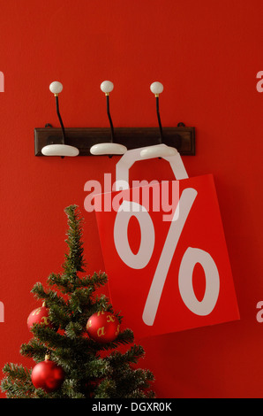 Einkaufstasche mit Prozent-Zeichen hängen nostalgisch Kleiderhaken, Weihnachtsbaum am vorderen Stockfoto