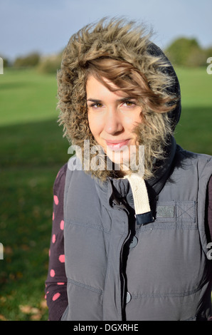 Junge Frau Lächeln auf den Lippen tragen ein Gilet mit pelzigen Kapuze Stockfoto