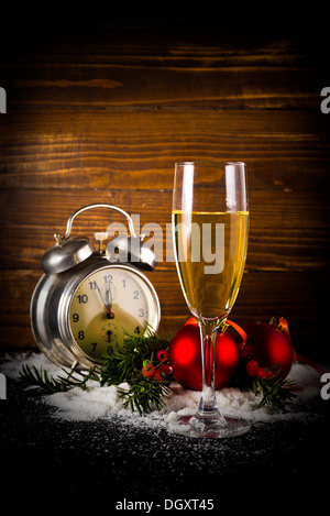 Weihnachtskugeln, ein Glas Champagner und Vintage Uhr fünf Minuten vor Mitternacht an Silvester. Stockfoto