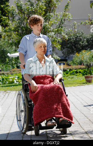 Enkel treibt seine Großmutter im Rollstuhl, im freien Stockfoto