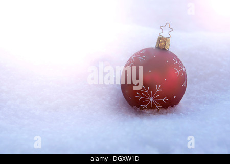 Rote Christbaumkugel liegen im Schnee Stockfoto